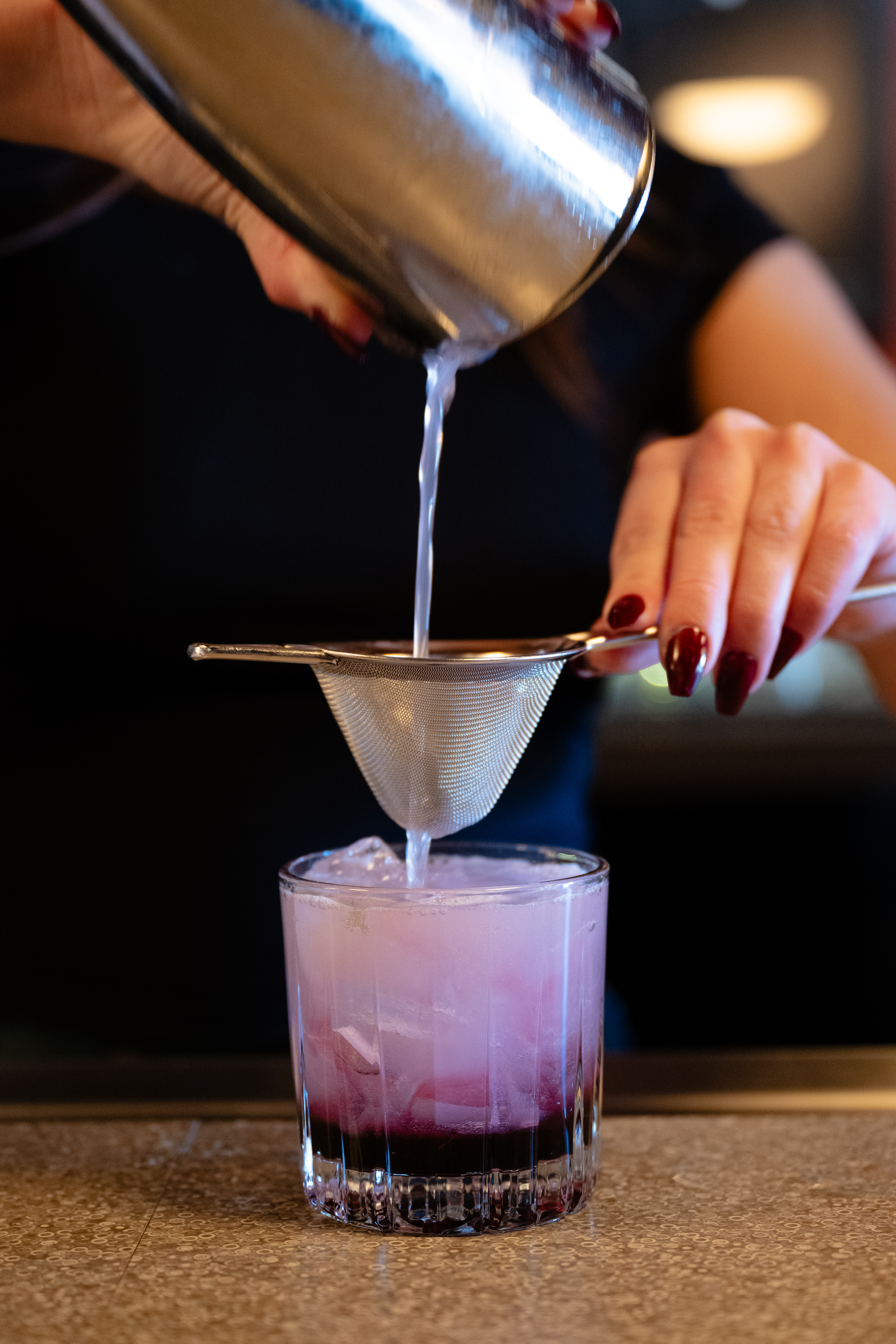 a hand holding a glass of beer on a table