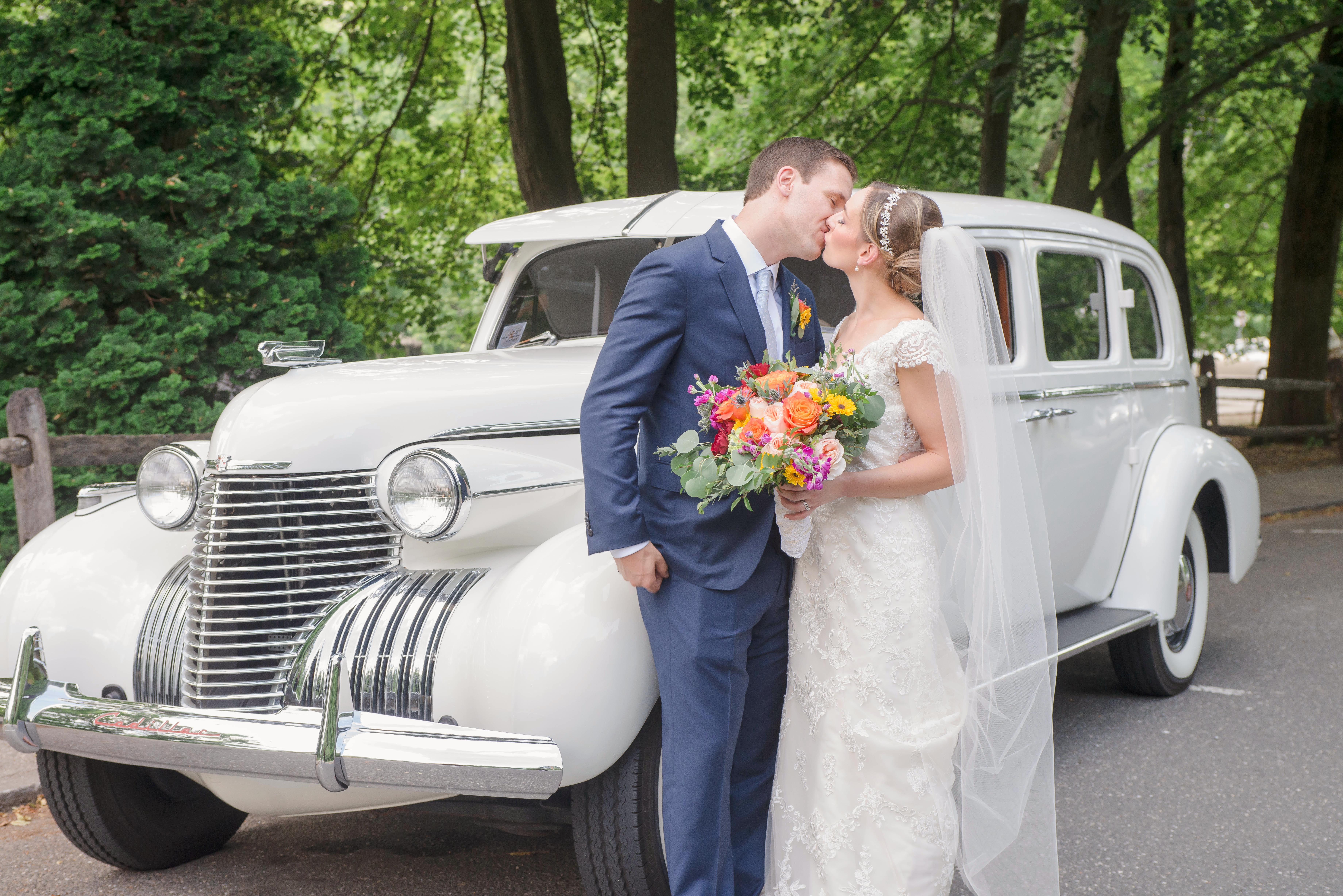 couple kissing at their spring wedding in front of the car