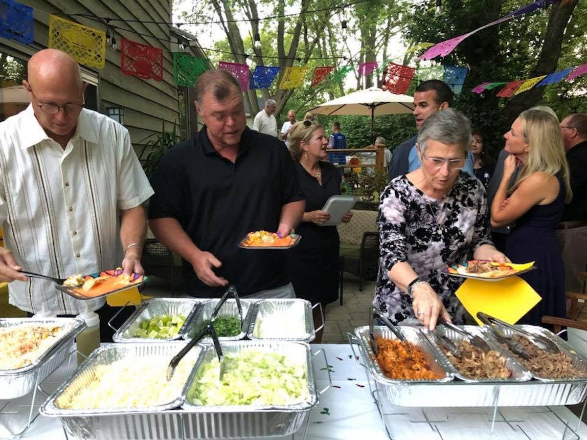 a group of people standing around a table with food