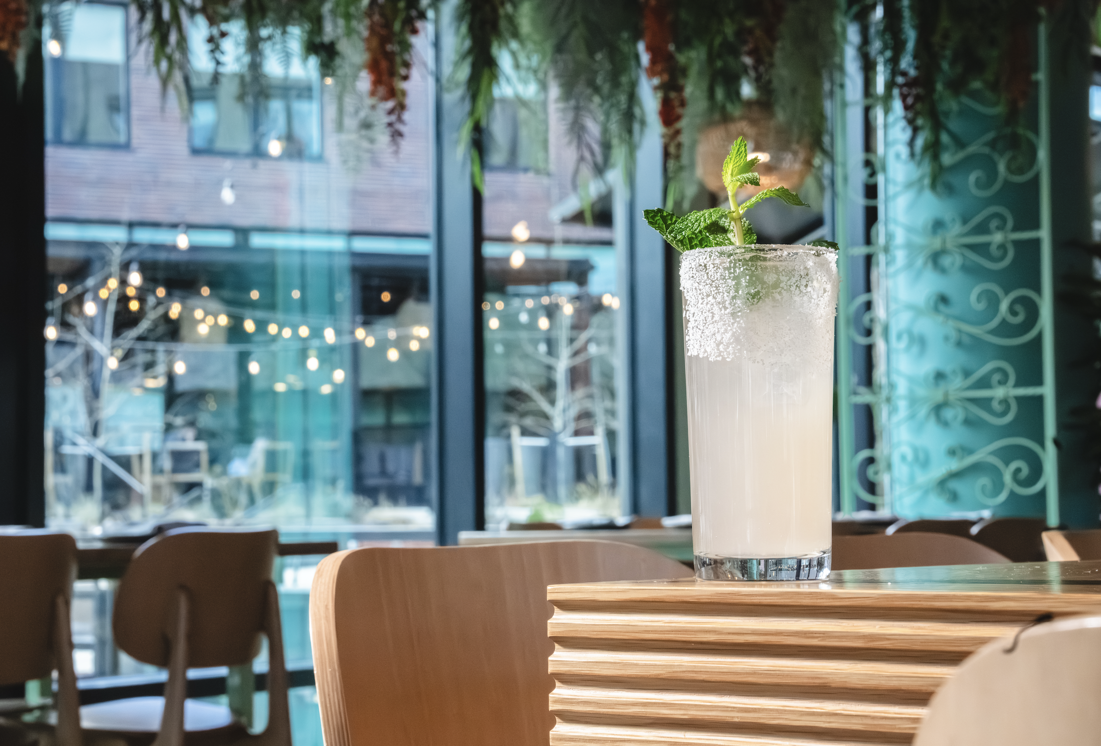 a glass of liquid with a leafy top on a table