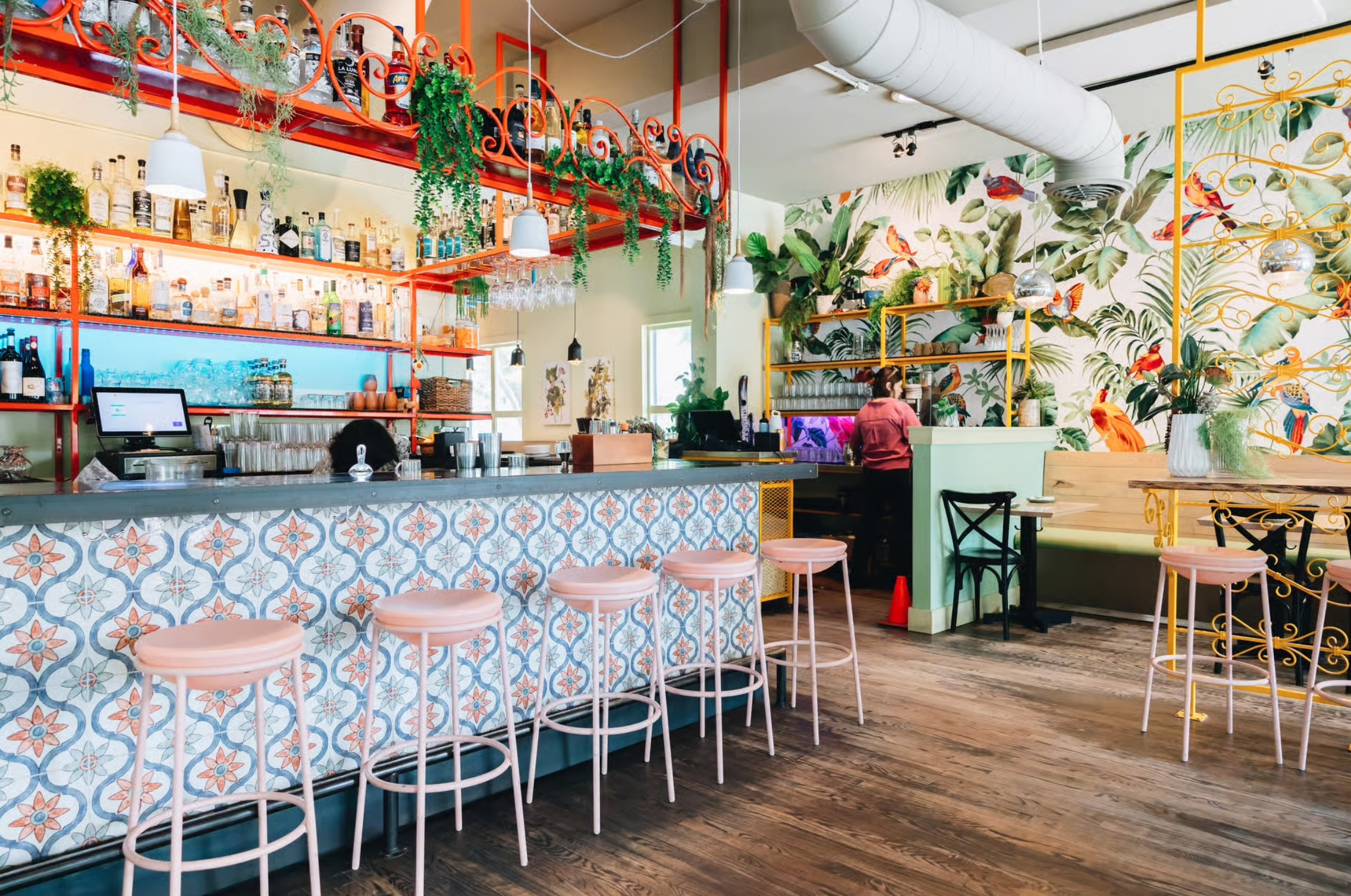 a bar with stools and shelves in a room with plants and flowers