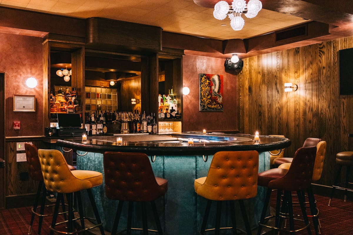 Warm and inviting bar area with a unique oval-shaped counter, mood lighting, and colorful artwork on the walls