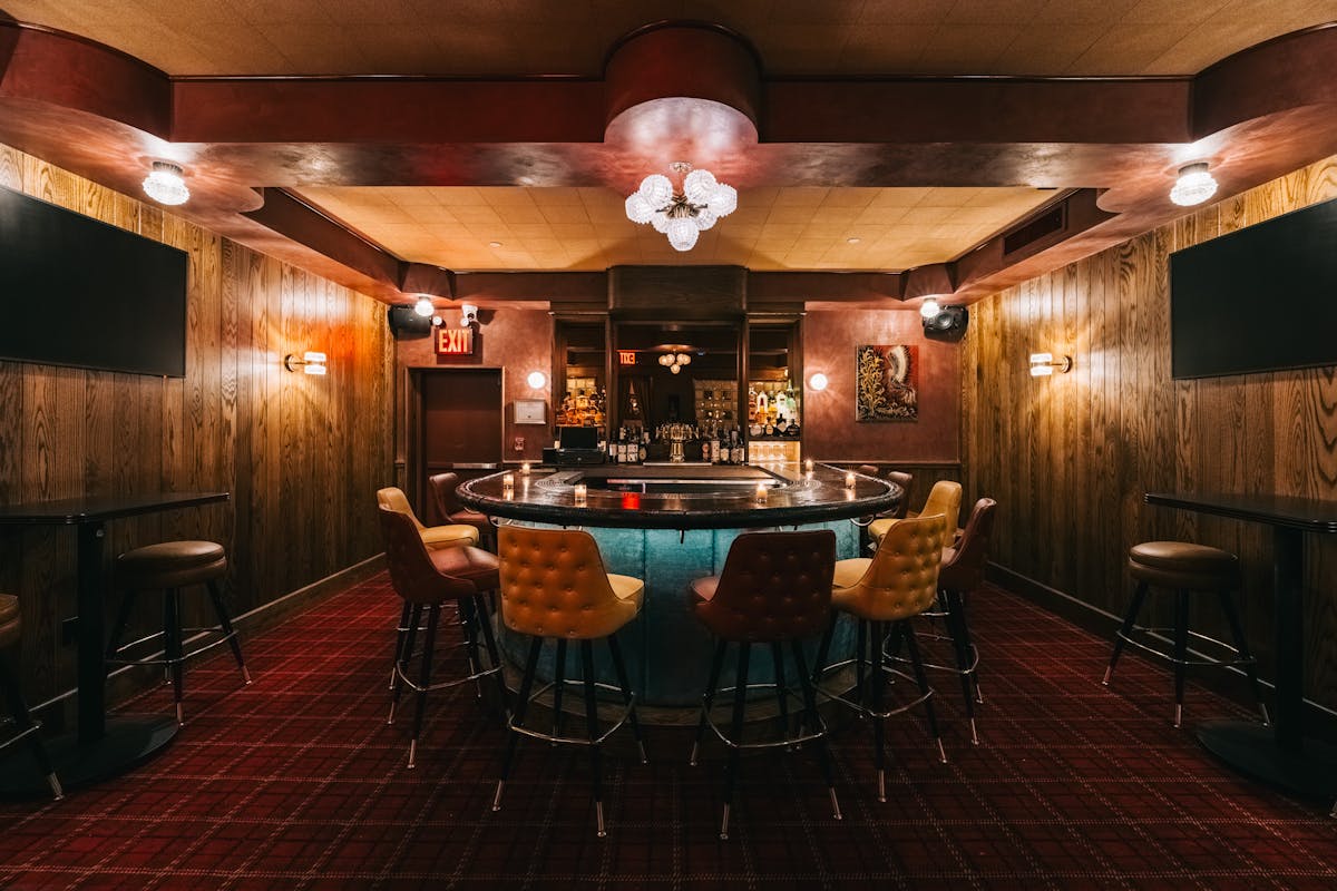 Retro-style bar featuring a glowing blue counter, eclectic lighting, and mismatched vintage seating