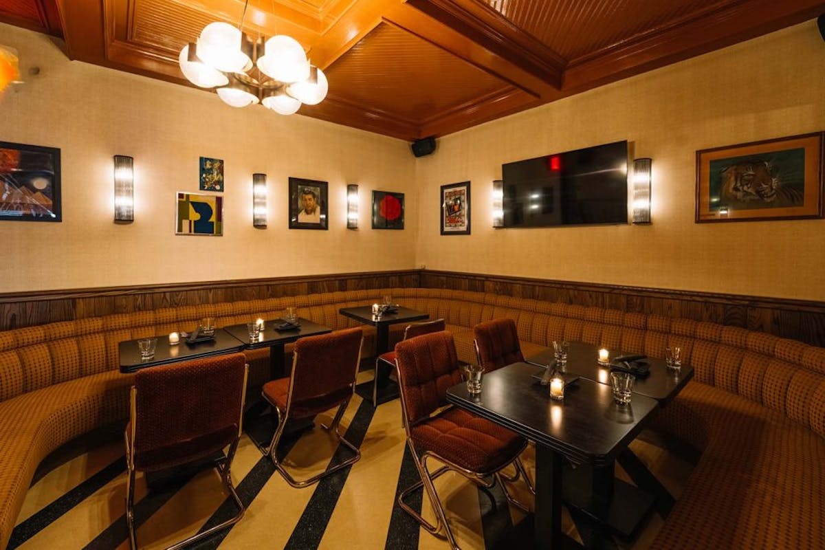 Warm-toned dining area featuring bar-style seating, eclectic wall art, and a stylish black and gold floor pattern