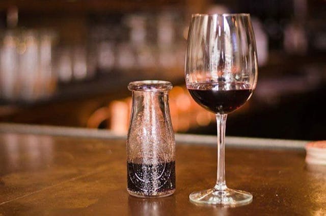 a glass of wine sitting on top of a wooden table