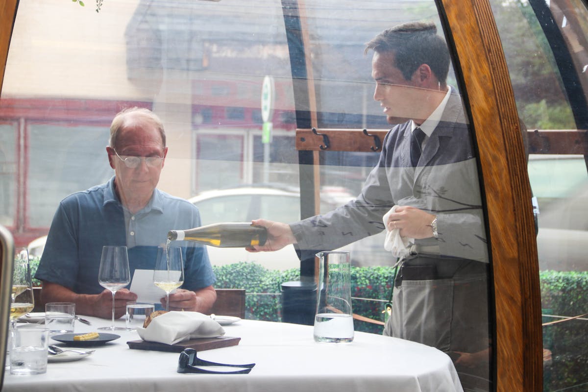 a person sitting at a table with wine glasses
