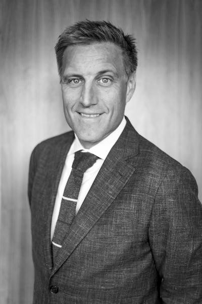 a man wearing a suit and tie smiling for the camera