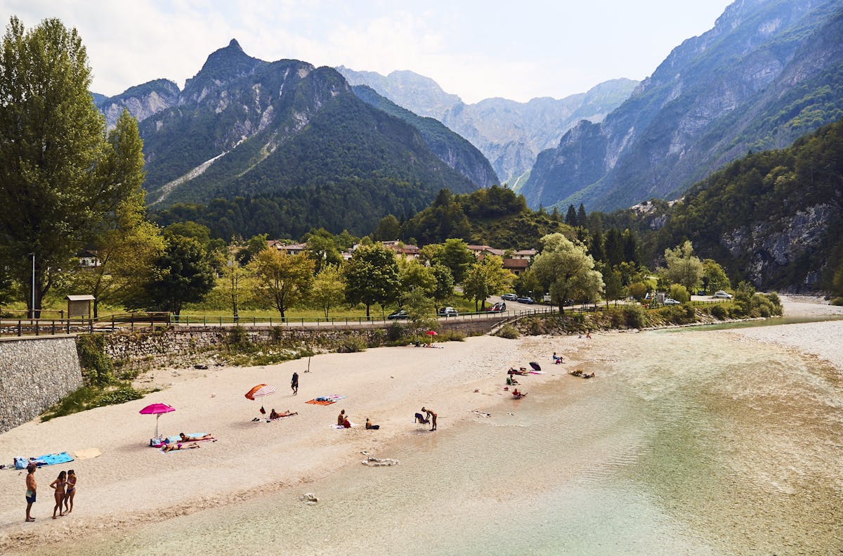 a group of people on a beach with a mountain in the background