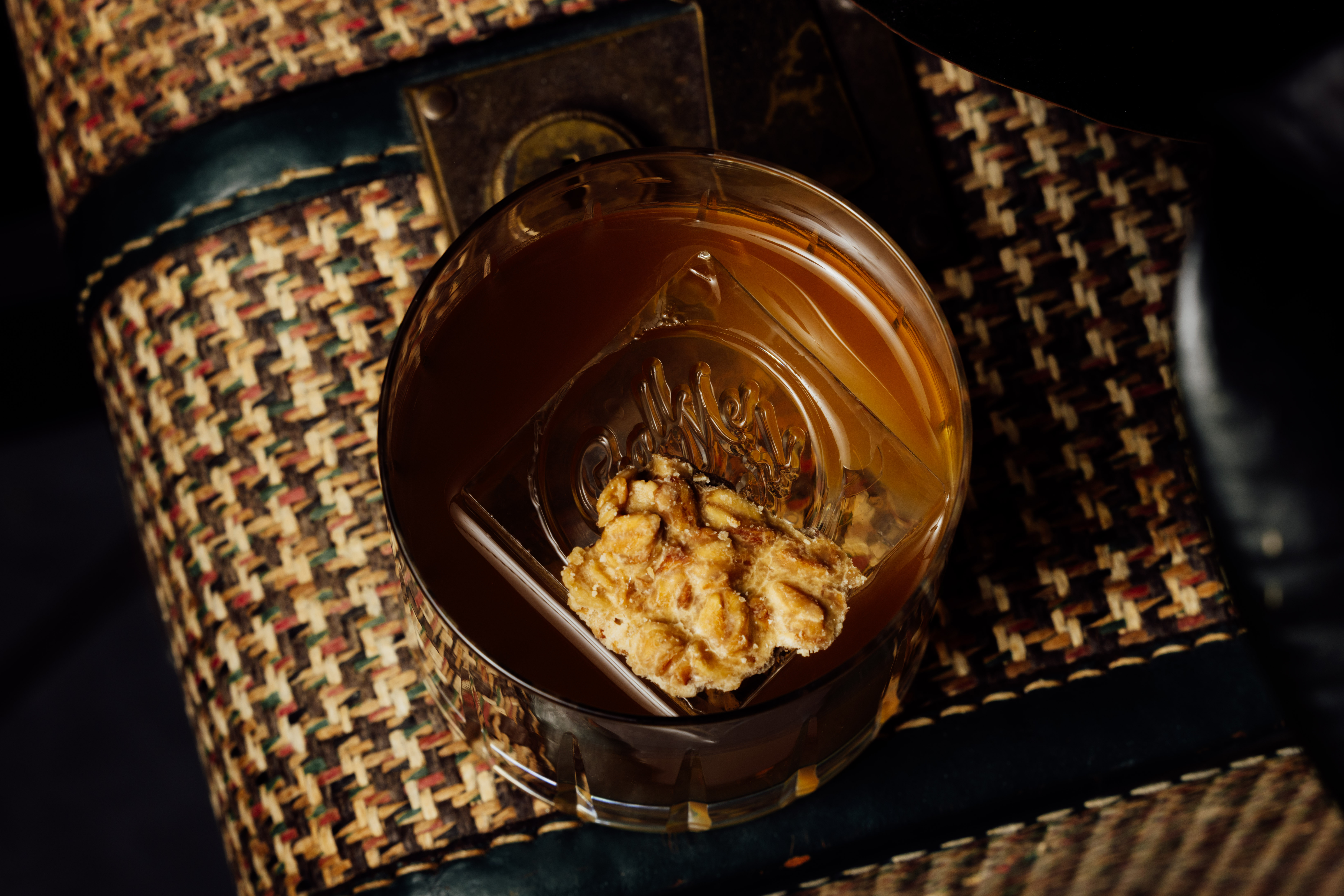 a glass of brown liquid with a piece of food on top