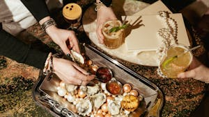 a person holding a spoon over a tray of food