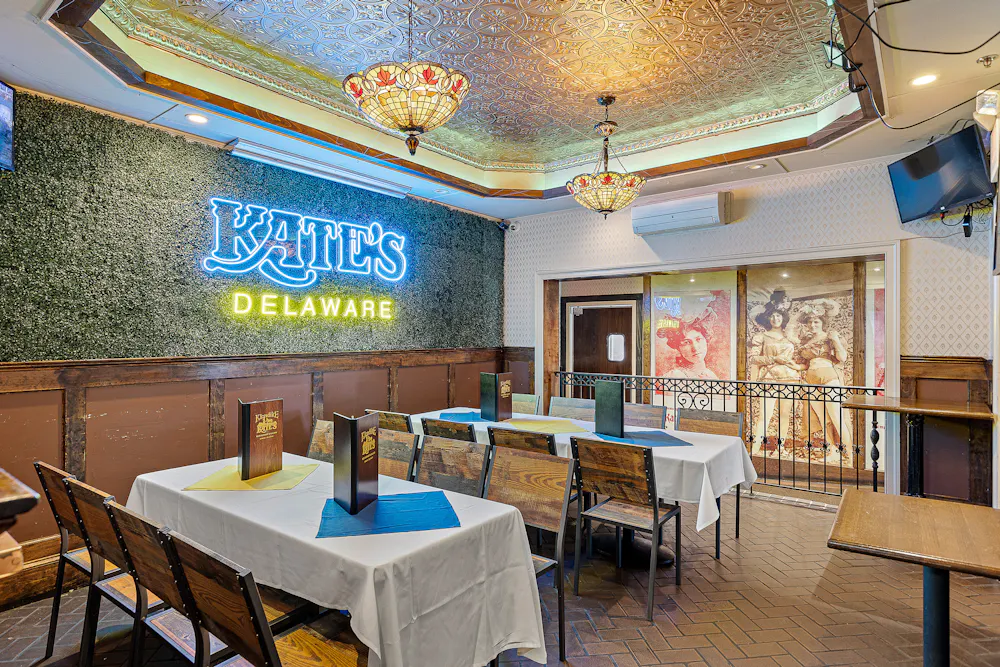 Private event room set with white-linen tables under Tiffany lighting at Klondike Kate's historic engagement party venue in Newark, Delaware