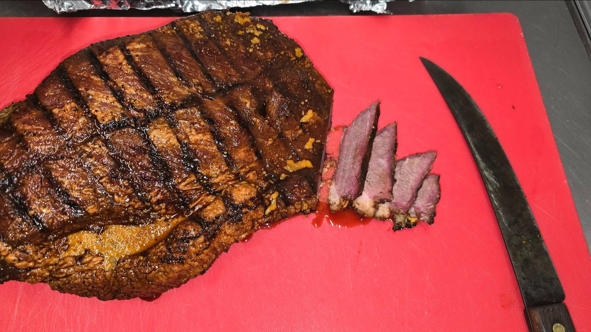 a piece of meat on a cutting board next to a knife