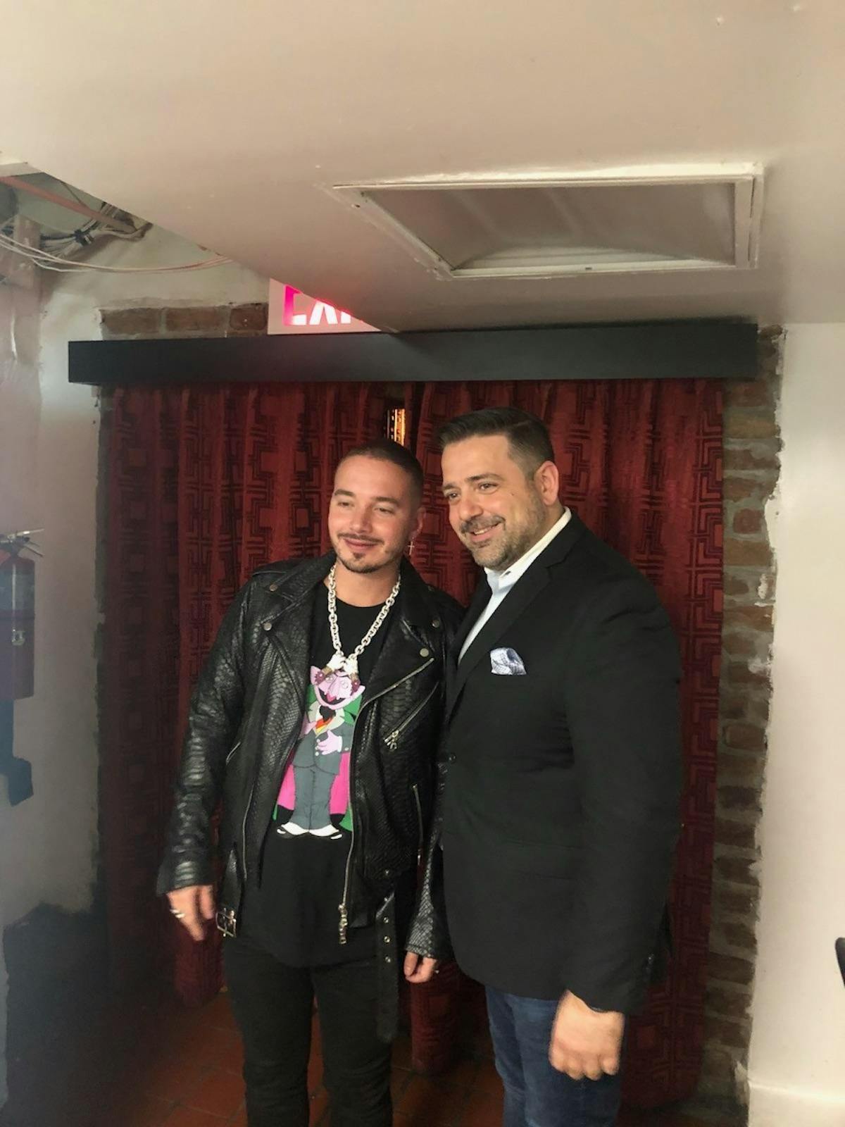 a man standing in front of J Balvin et al. posing for the camera