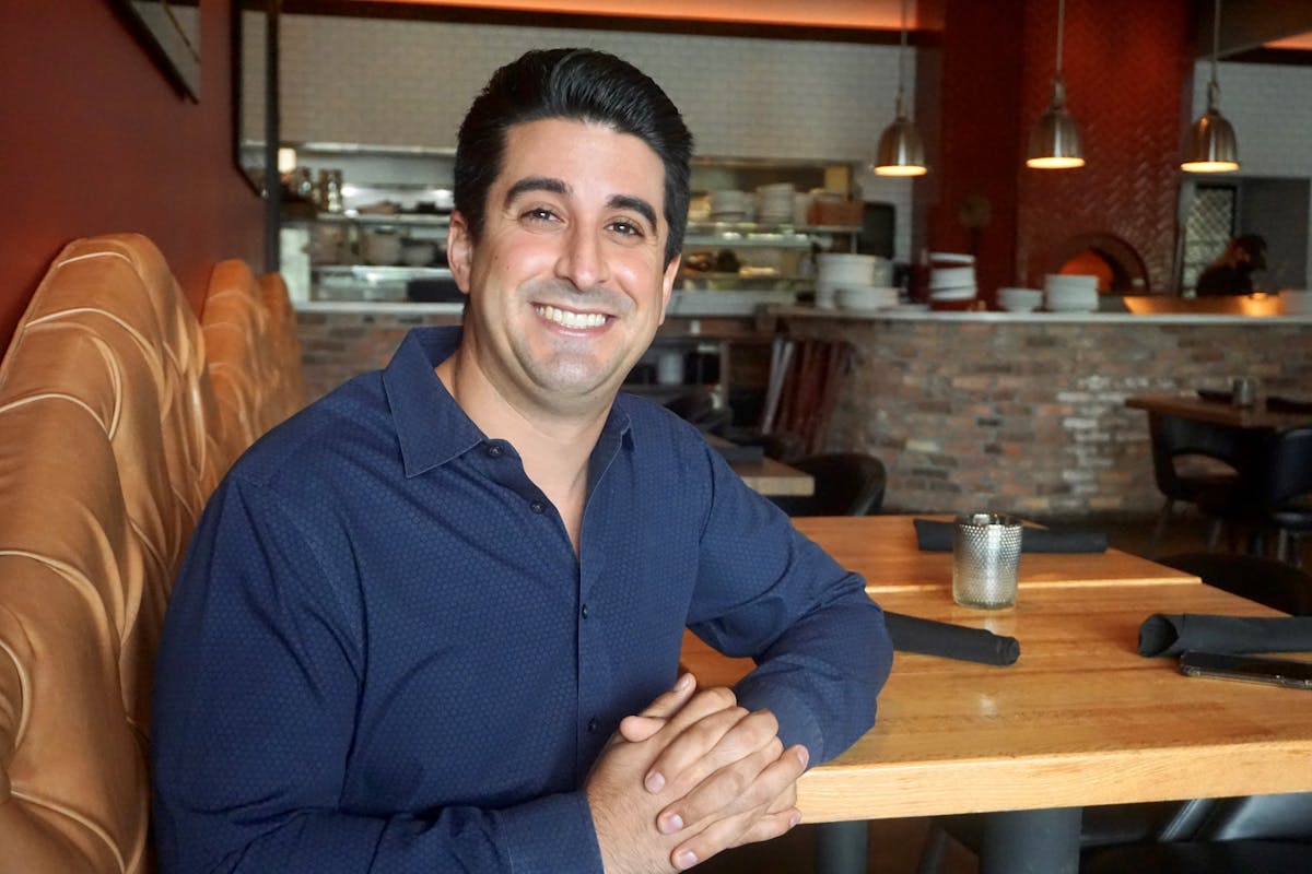 a man sitting at a table and smiling at the camera