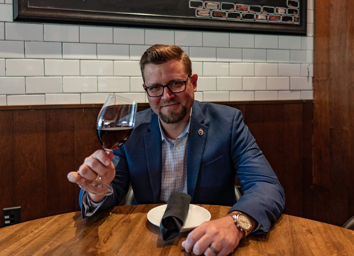 a man sitting at a table with wine glasses