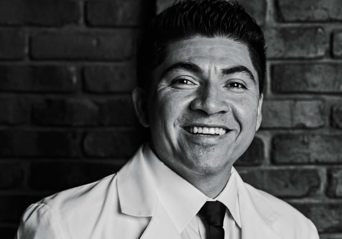 a man wearing a suit and tie smiling at the camera