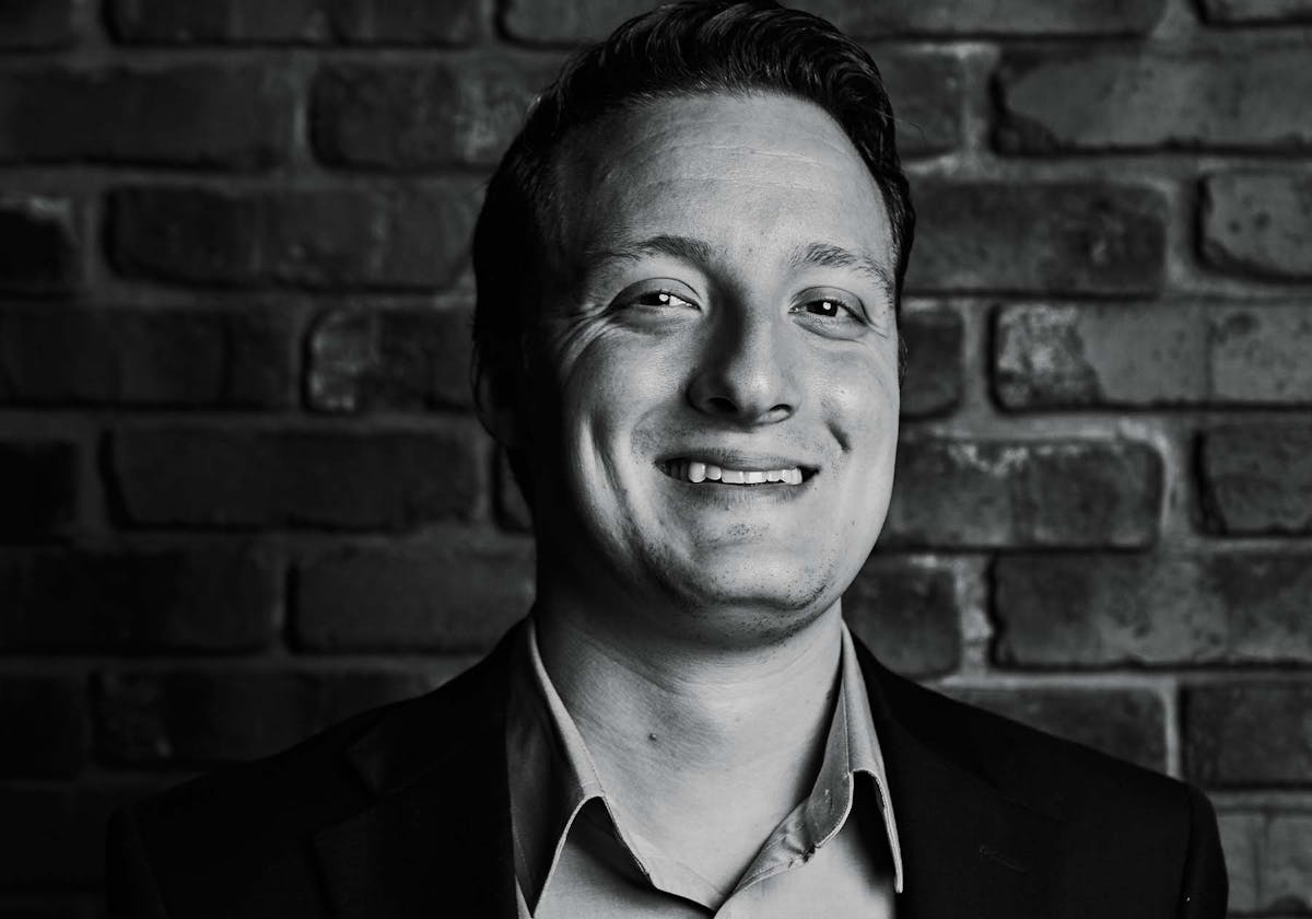 a man standing in front of a brick wall posing for the camera