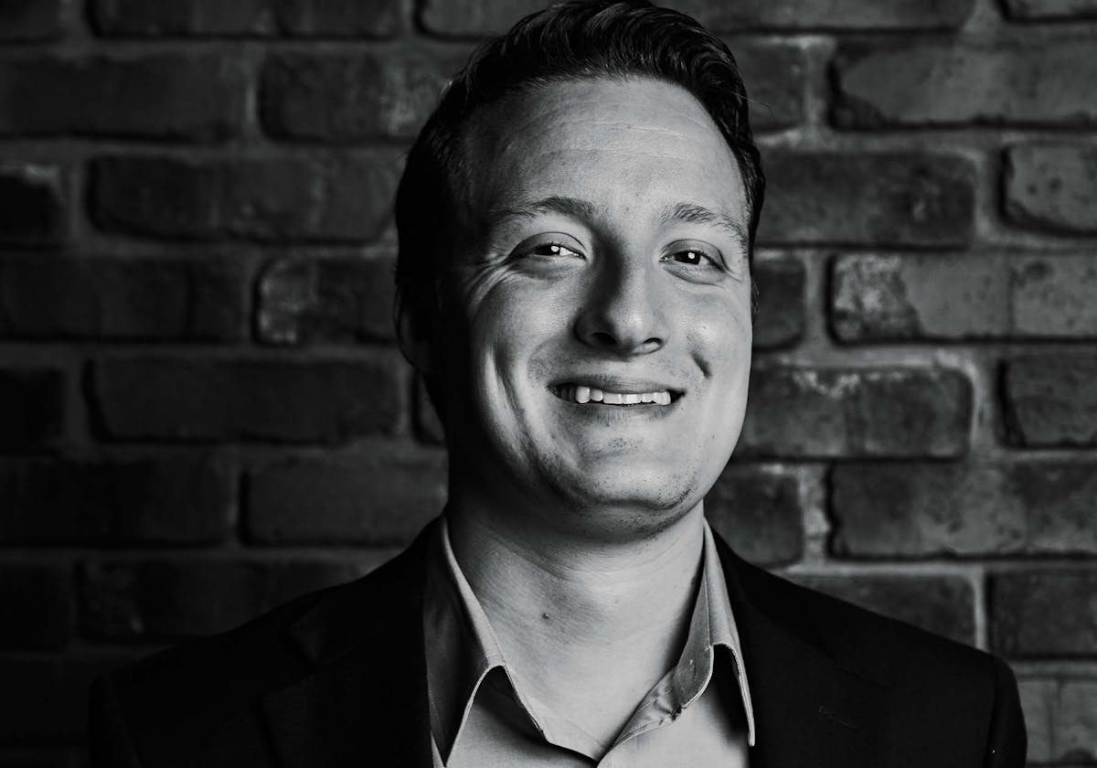 a man standing in front of a brick wall posing for the camera