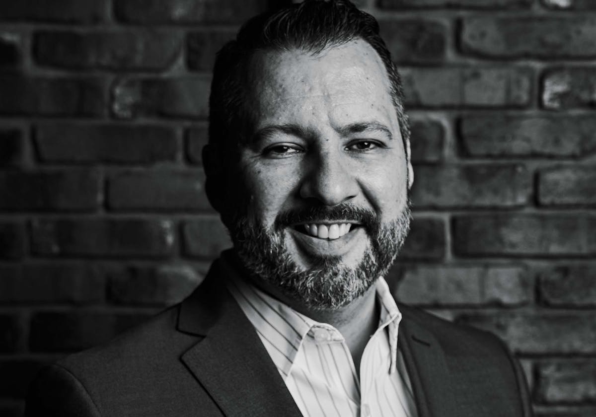 a man wearing a suit and tie in front of a brick wall
