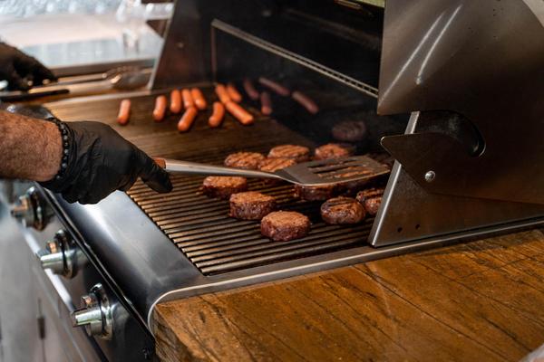 a person cooking hot dogs on a grill
