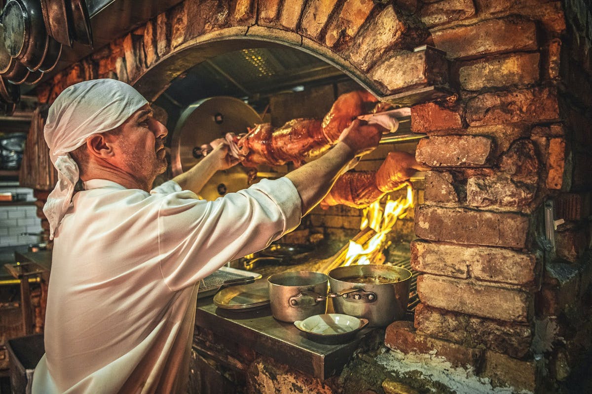 a man grilling over live fire rotisserie