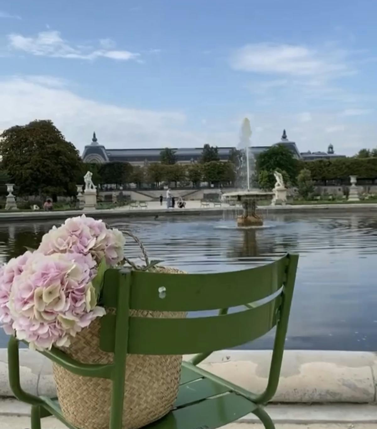 a green chair with a bouquet of flowers in front of a fountain