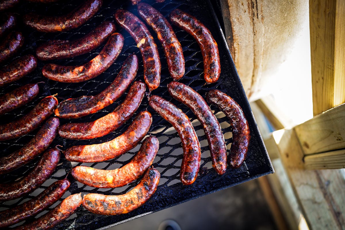 a bunch of hot dogs cooking on a grill