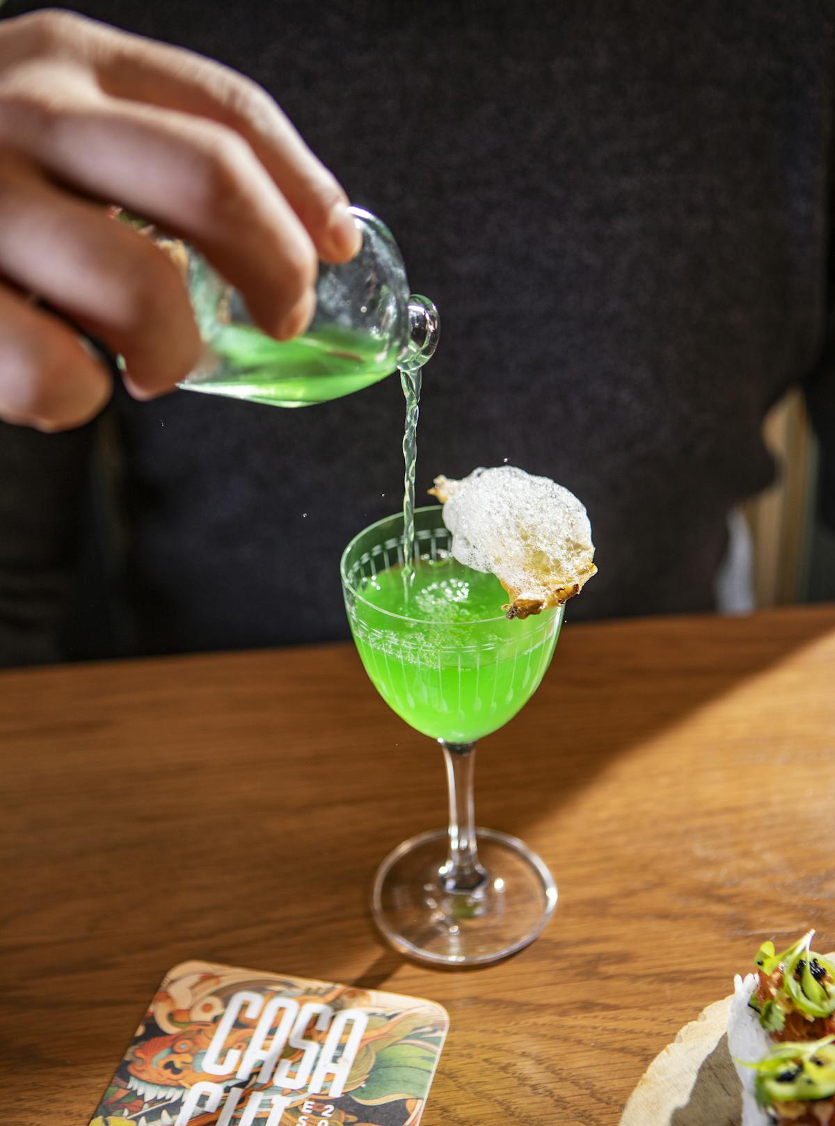 a person holding a wine glass sitting on top of a wooden table
