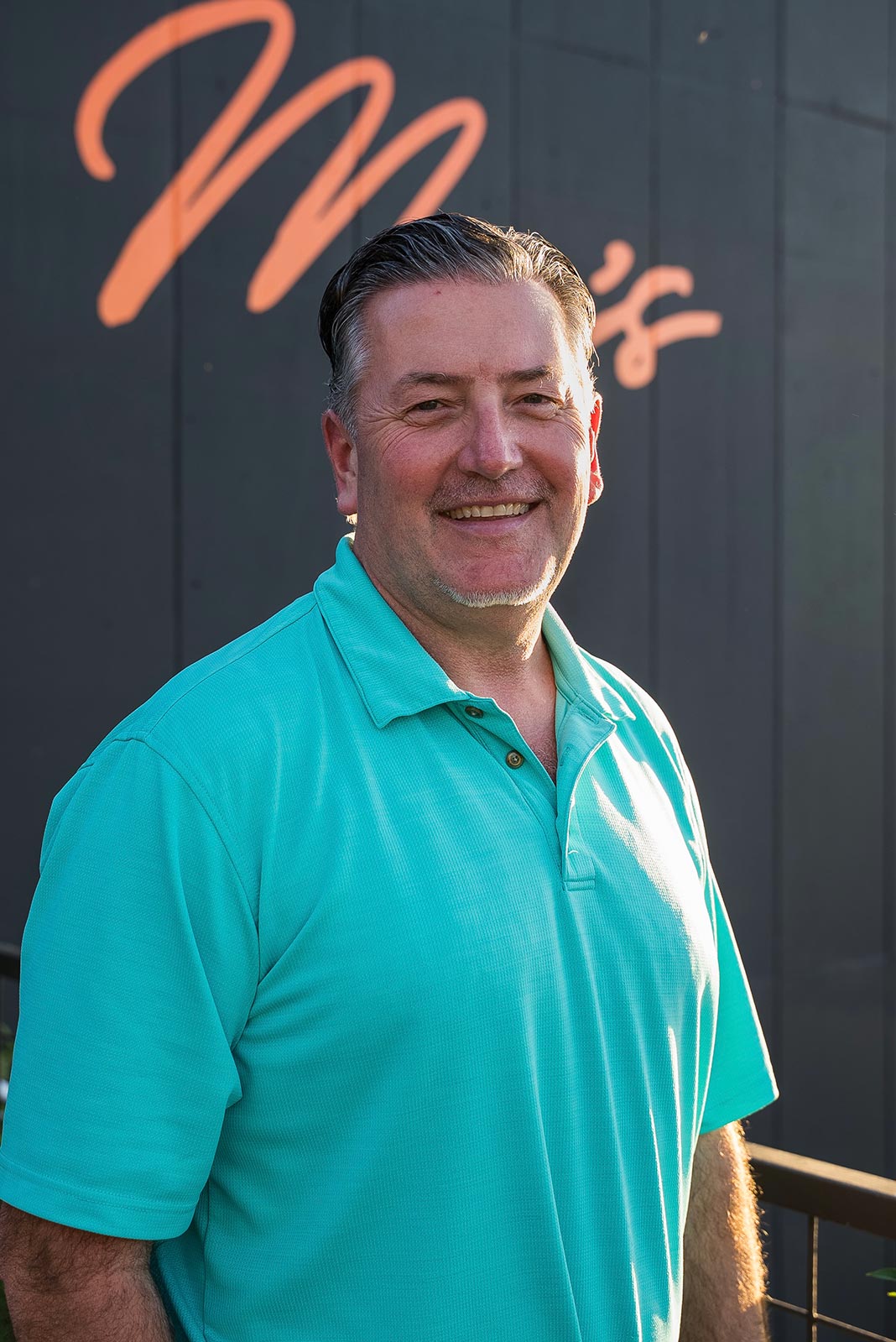 General manager, Scott Buchan, standing in front of black panel wall