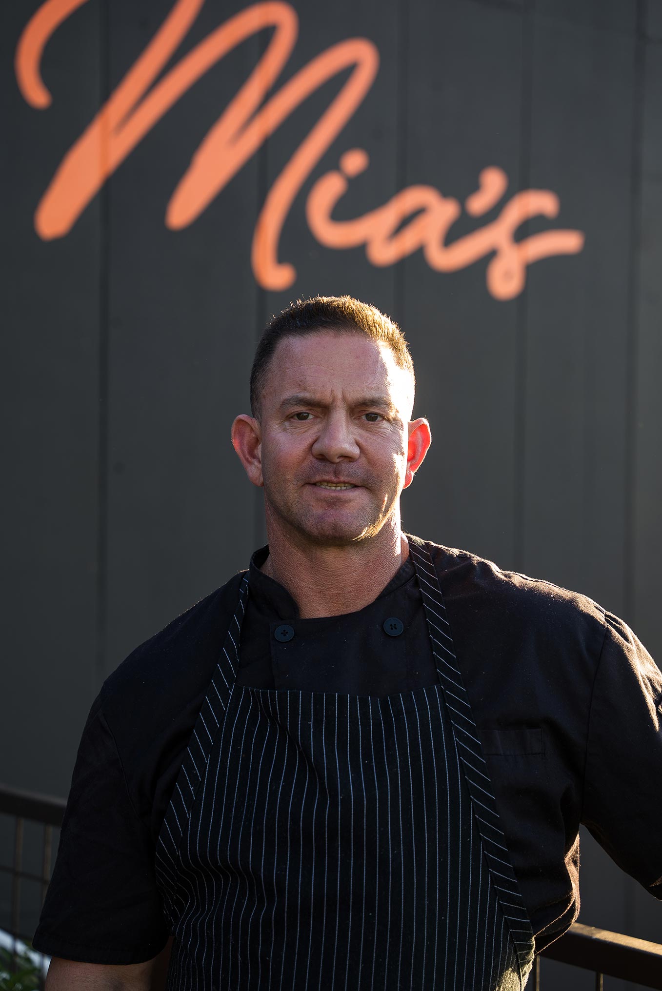 Head chef, Ben Lieberman, standing in front of black panel wall