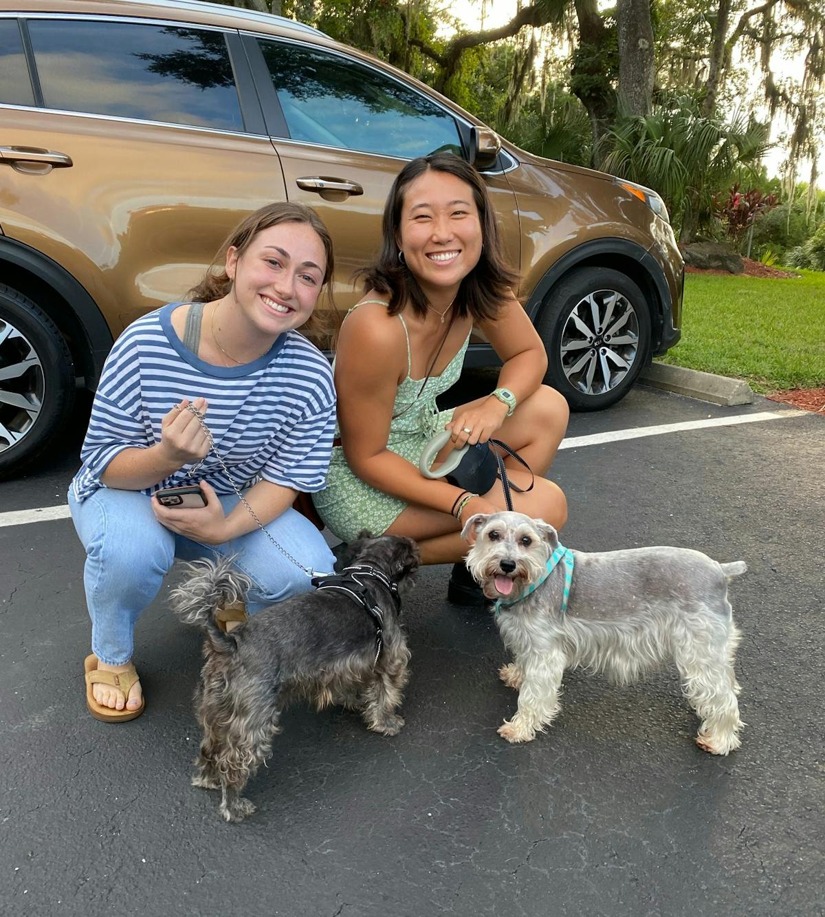 a woman holding a dog in a car posing for the camera