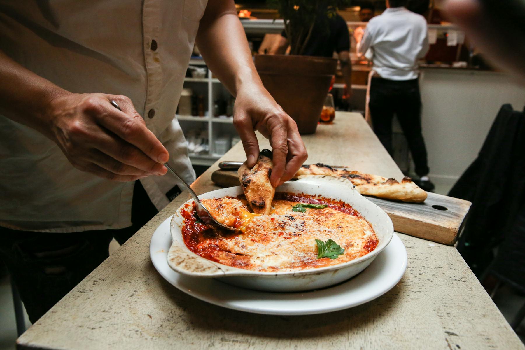 a woman cutting a pizza on a plate