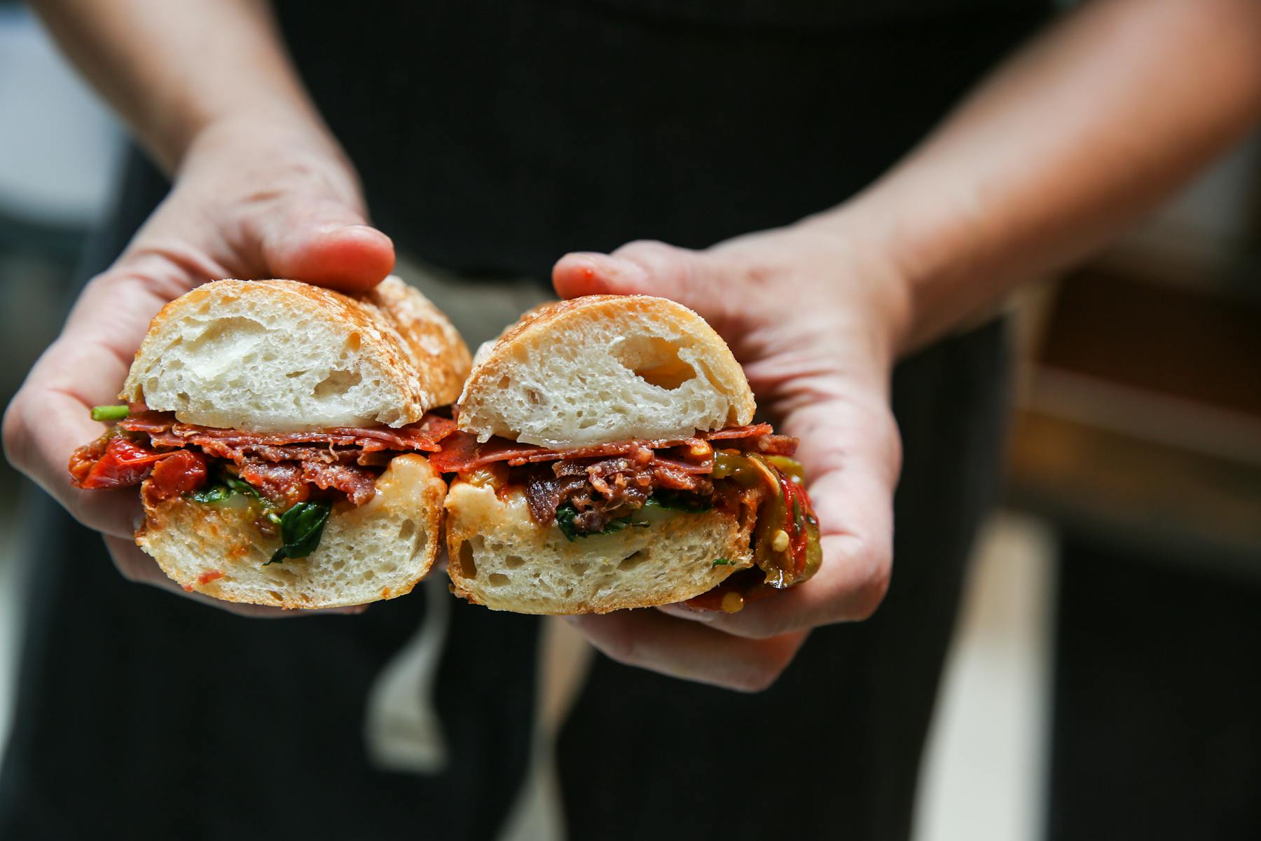 a close up of a person holding a sandwich in his hand
