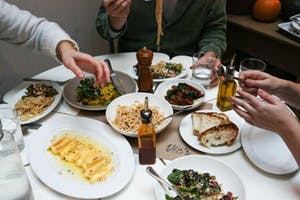 a group of people sitting at a table with a plate of food