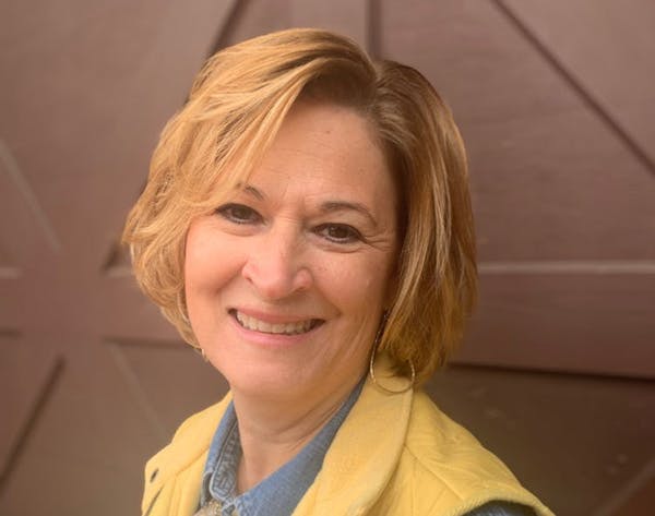 a woman wearing glasses and smiling at the camera