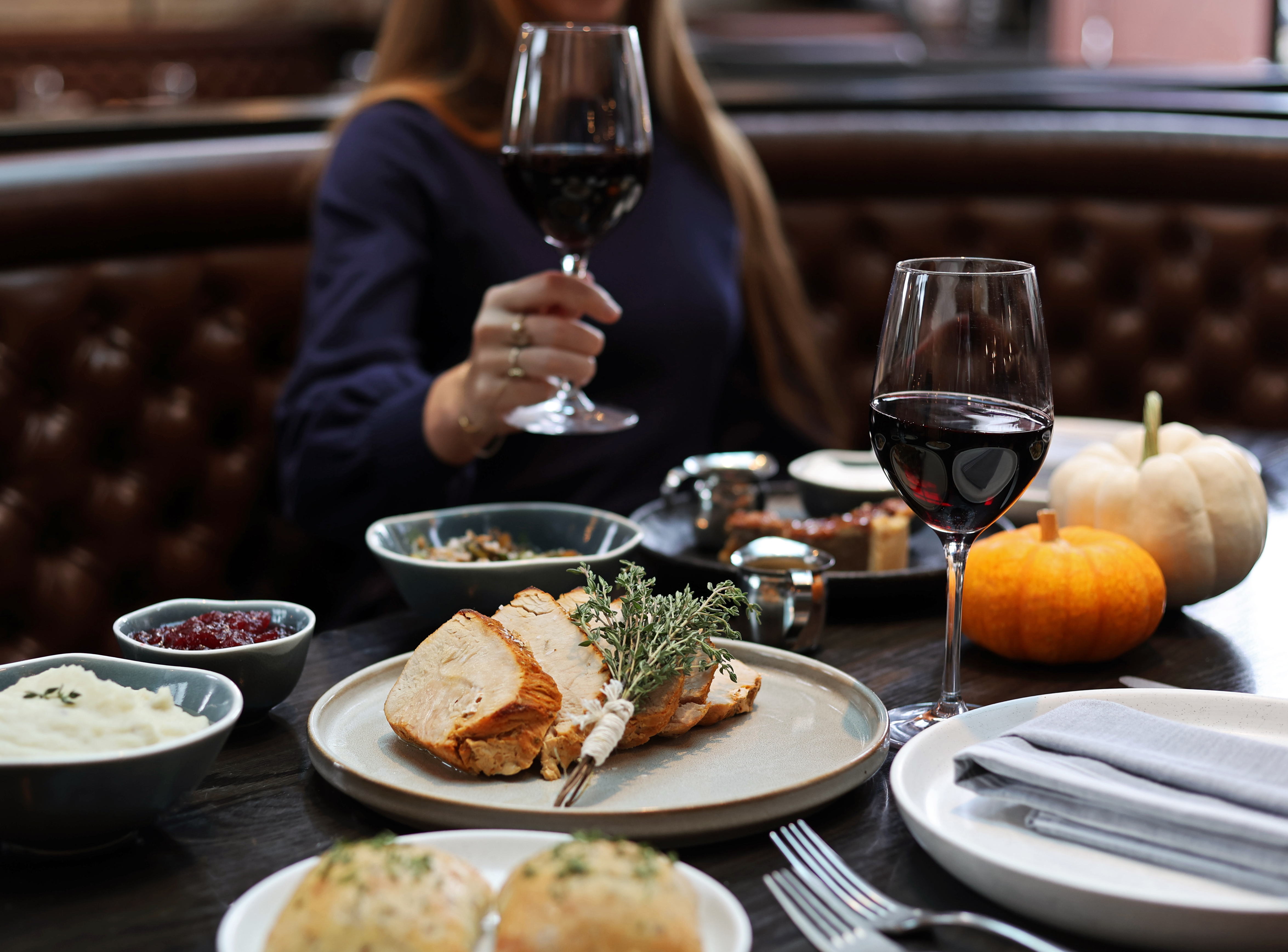 a woman sitting at a table with food and a glass of wine