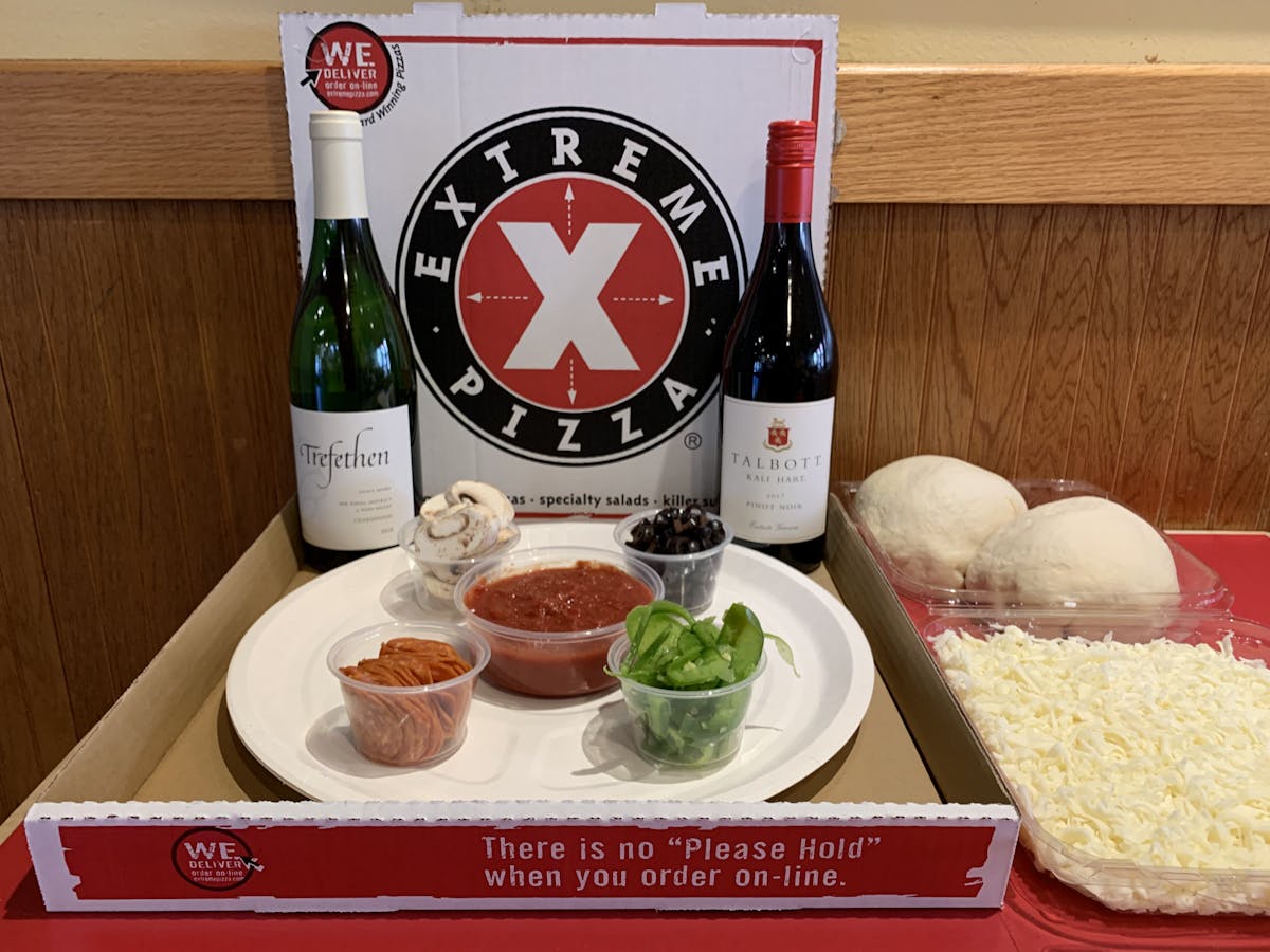 wine bottles with a plate of toppings and pizza dough balls