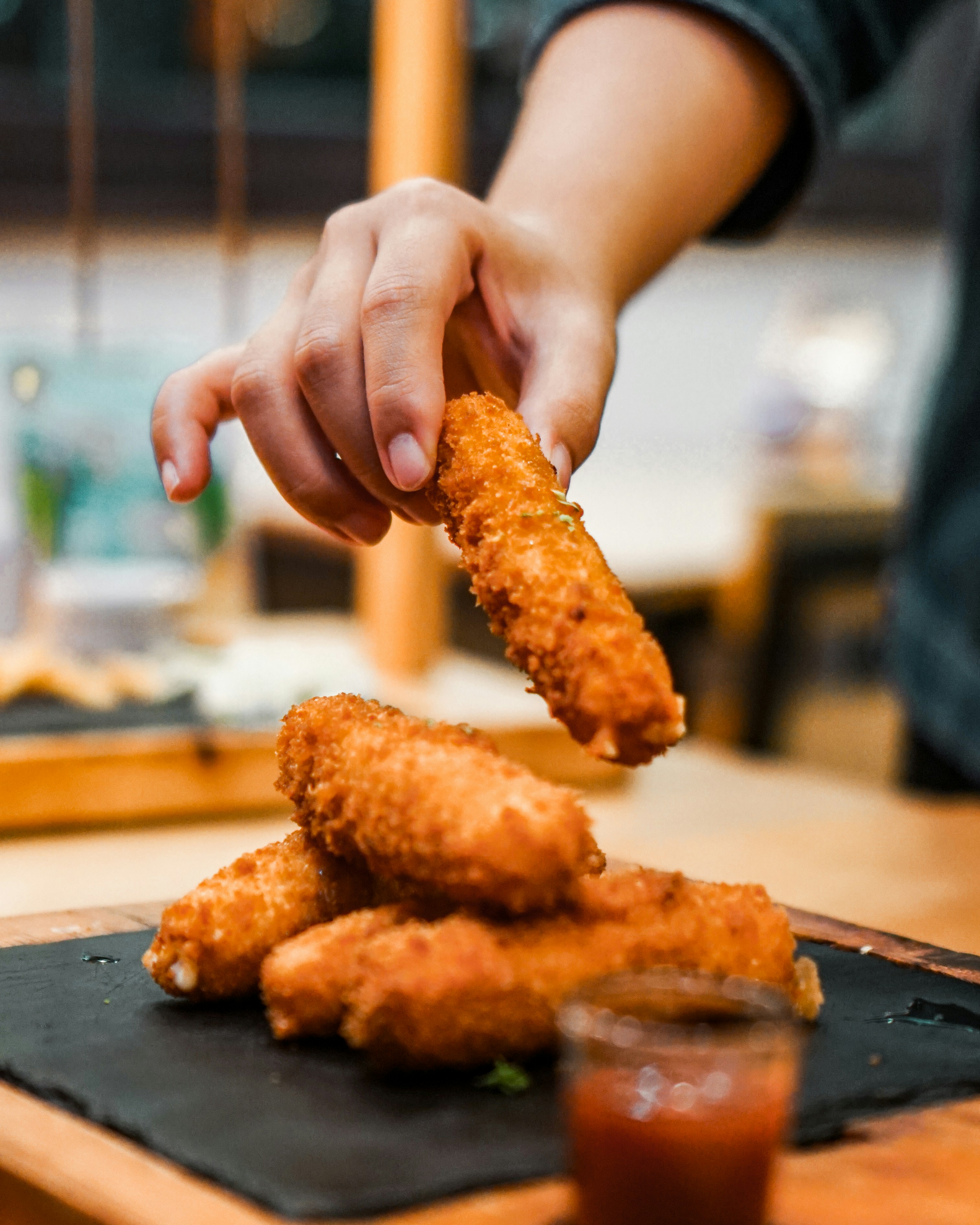 a hand holding a piece of meat on a cutting board