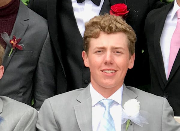 a man wearing a suit and tie smiling at the camera