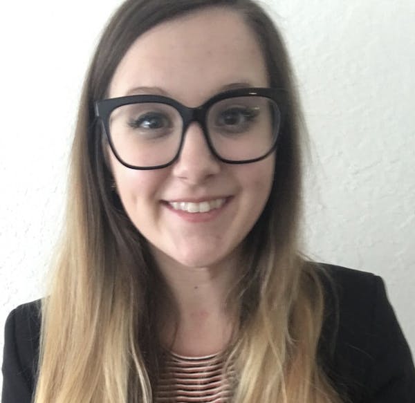 a woman wearing glasses and smiling at the camera