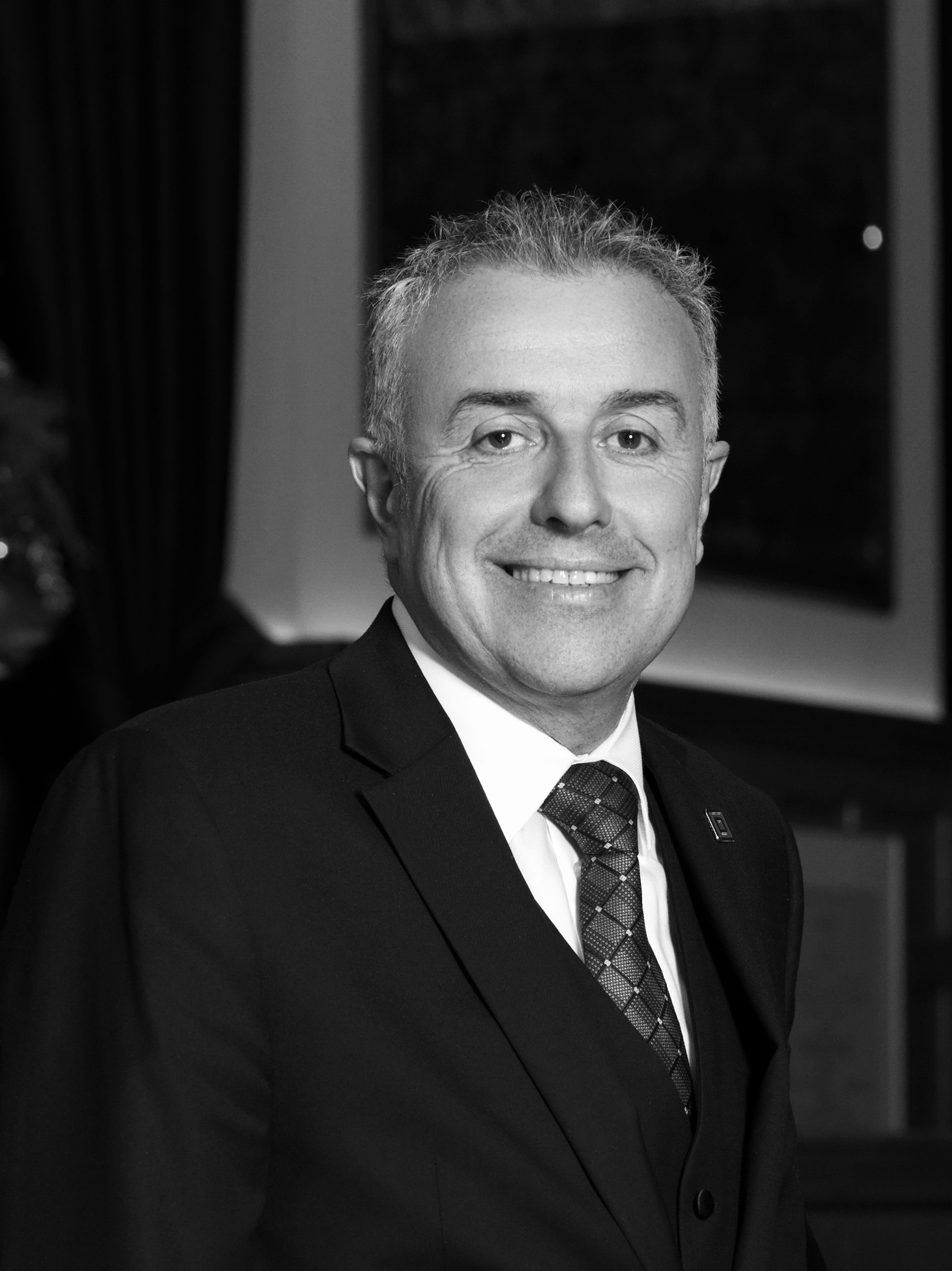 a man wearing a suit and tie smiling at the camera