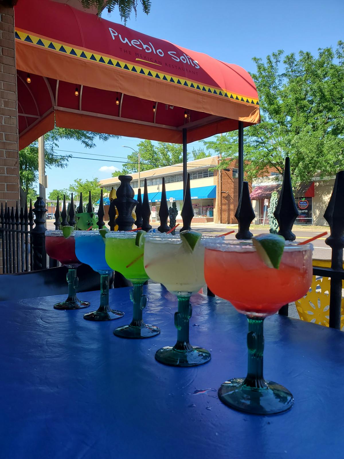 a group of people sitting at a table with a blue umbrella