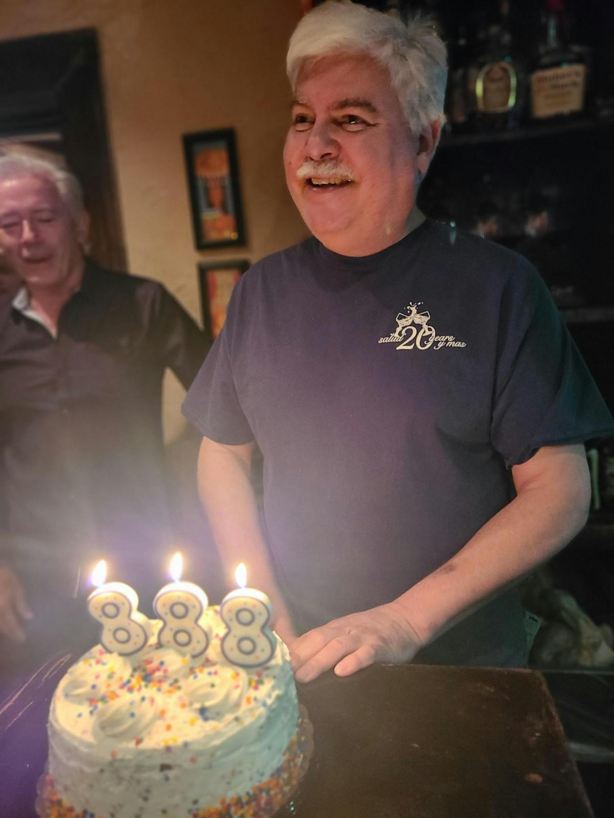 a man standing in front of a birthday cake with lit candles