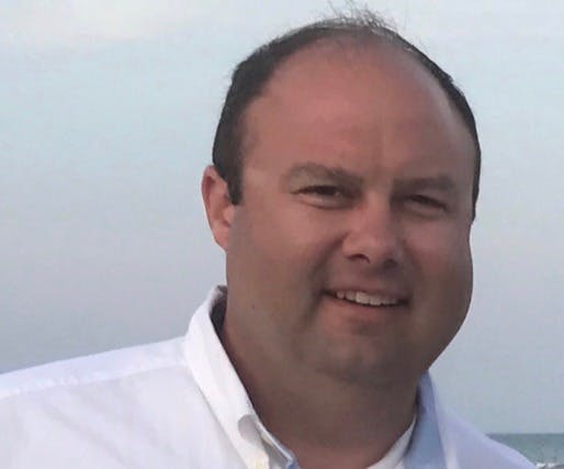 a man wearing a suit and tie smiling at the camera