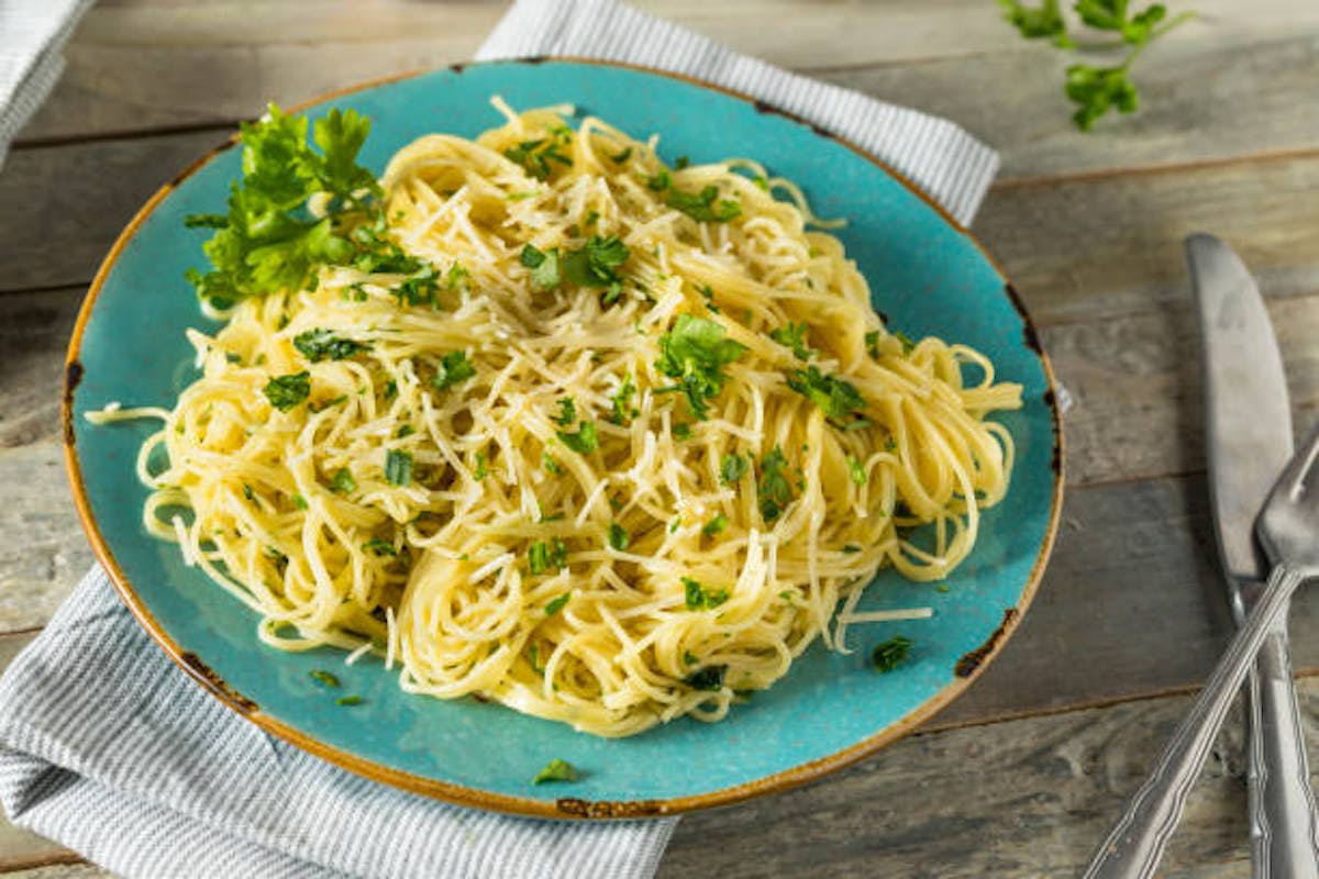 a plate of angel hair pasta with a cherry tomato and prosciutto sauce