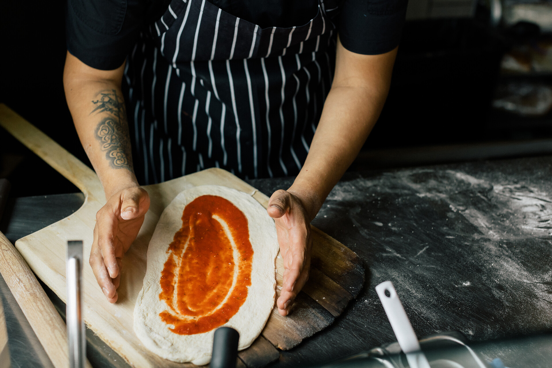 a close up of chef putting sauce on pizza