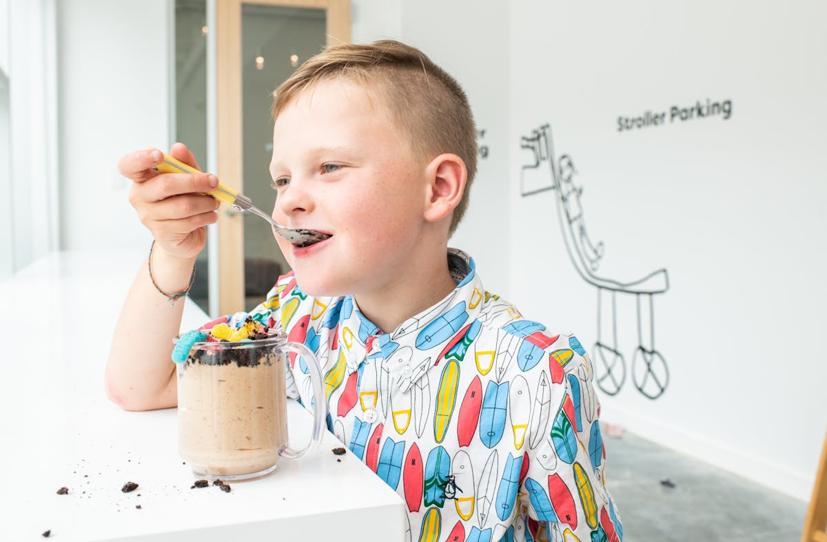 a young boy sitting at a table eating food