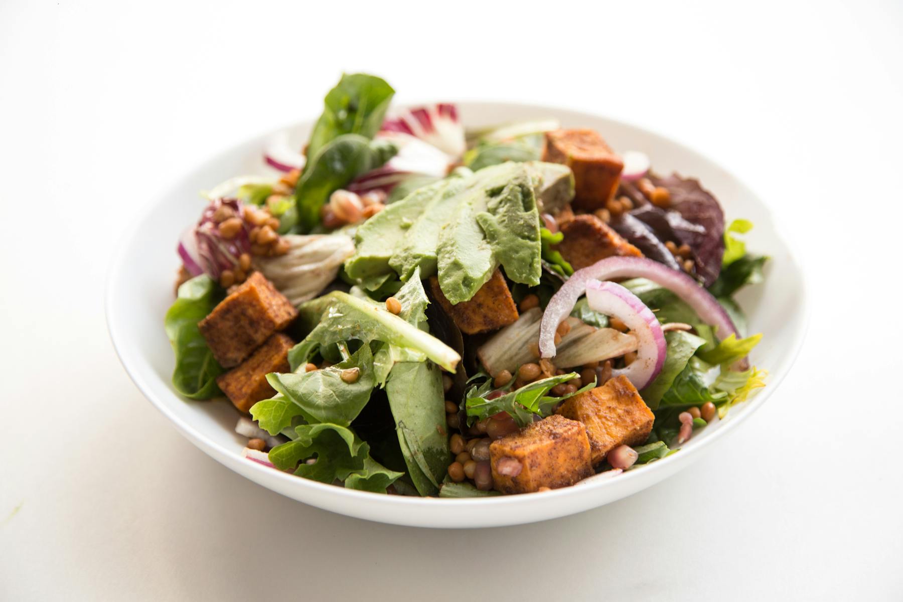 a white bowl filled with different vegetables and croutons