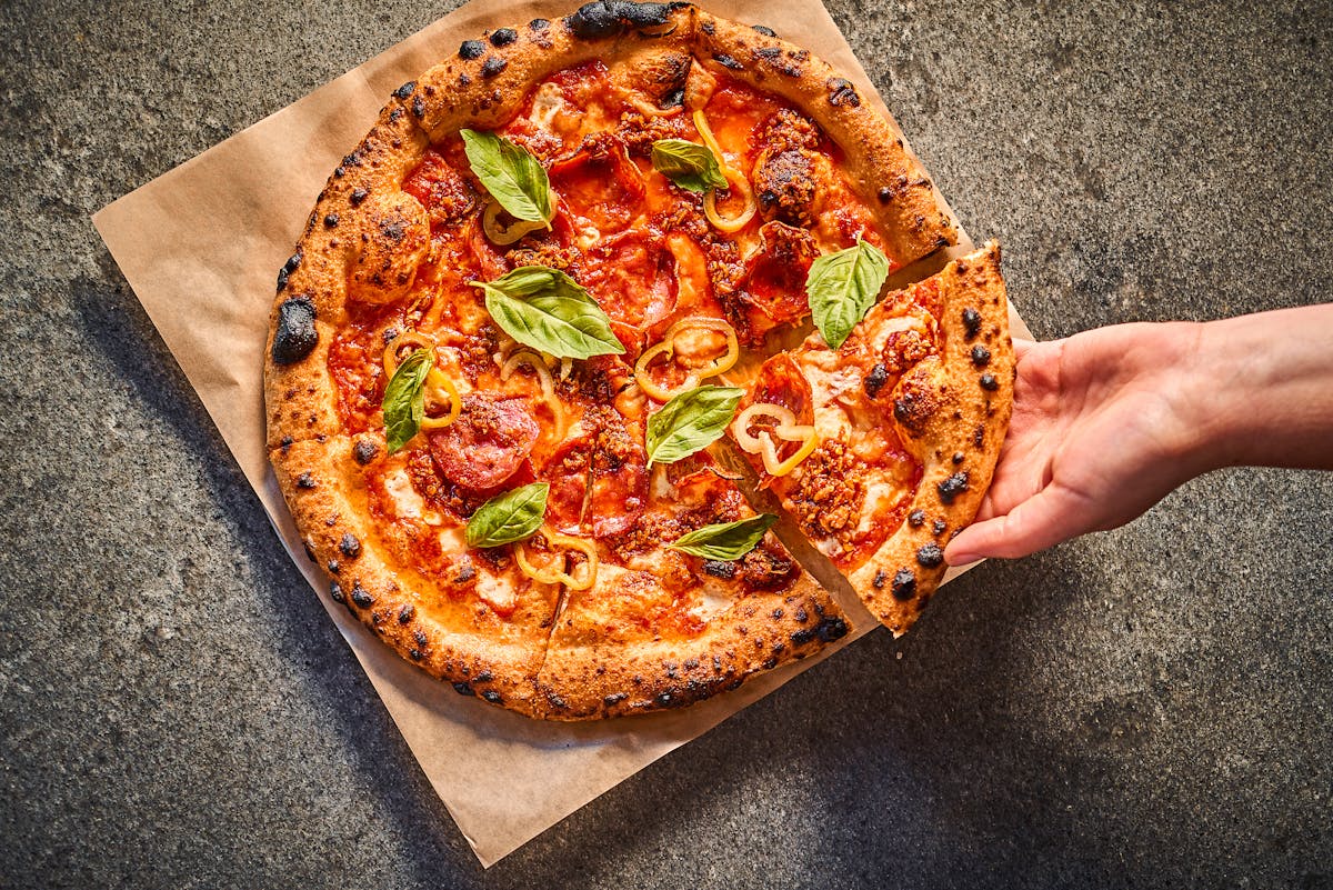 wood-fired pizza with pepperoni, peppers and fresh basil 