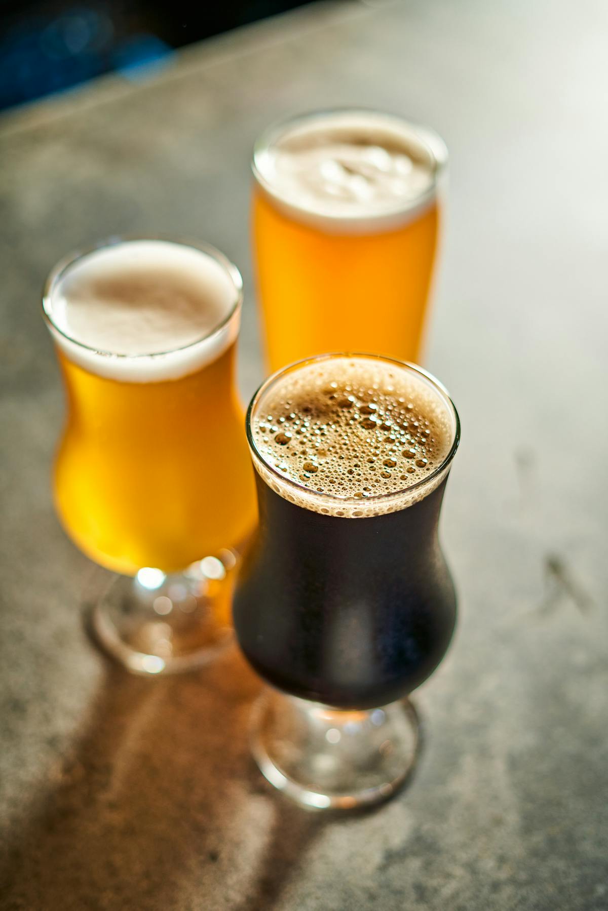 three glasses of craft beer on a stone countertop 
